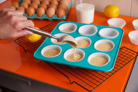 A closeup shot of a cooking form filled with lemon muffins with ingredients on the table