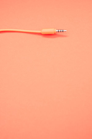 A vertical shot of a headphone cable on a pastel orange background for a copy spaceの写真素材