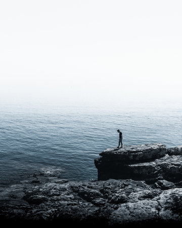 How small we are compared to nature - man standing on a cliffの写真素材