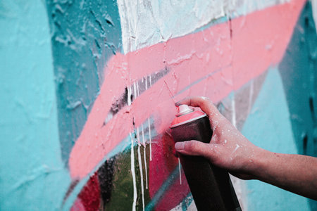 A closeup shot of an artist's hand holding a paint spray can for drawing graffiti on the wall