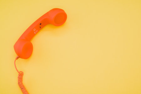 A classic orange handset on pastel yellow background for a copy spaceの写真素材