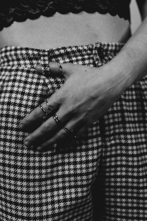 A grayscale shot of a female in checkered pants with many thin rings on the handの写真素材