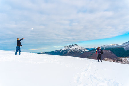 A beautiful shot of the male and female playing with snowballs in Oiertzun, Basque, Spainの写真素材