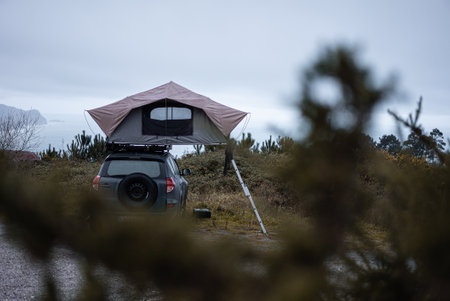 A car rooftop tent for camping on the roof rack of an off-road car by the lakesideの写真素材