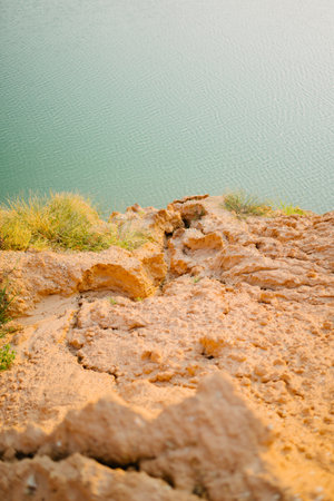 A vertical shot of a rock covered in little grass looking into the ocean. Perfect for summer wallpaperの写真素材