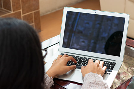 young man sitting in armchair, doing home office, typing on laptop