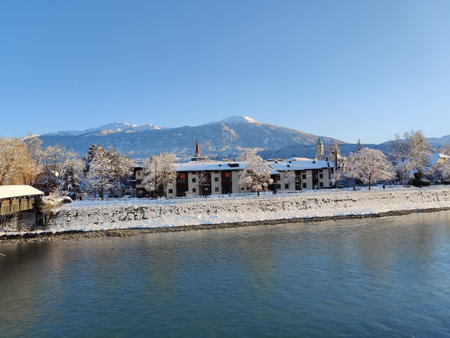 A riverbank with houses and mountains covered with snowの写真素材