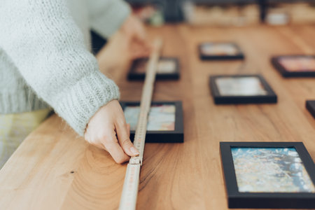 A closeup shot of human hands measuring the wooden board with a rulerの写真素材