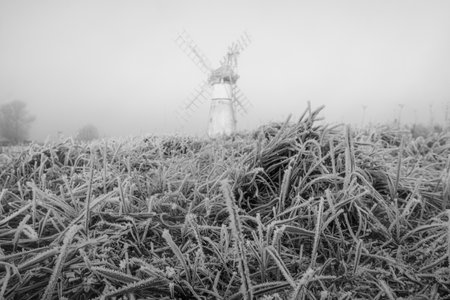 A grayscale shot of a windmill with mist over it in How Hill, Norfolkの写真素材
