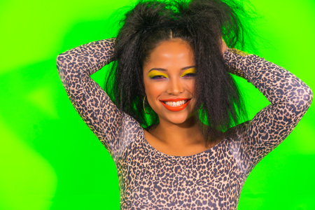 A closeup portrait of a positive cheerful woman in bright makeup posing isolated on a green...