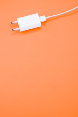 A vertical shot of USB charger isolated on orange background