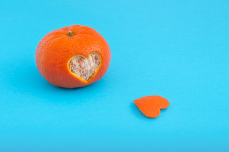 A closeup shot of orange with heart cut shaped isolated on blue backgroundの写真素材