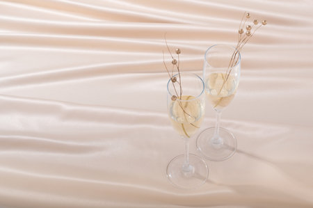 A high angle shot of two glasses of champagne with golden pearls on beige clothの写真素材