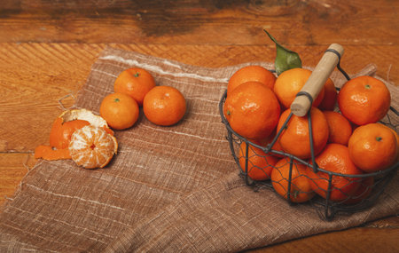 Fresh tangerines in a metal basket on a wooden backgroundの写真素材