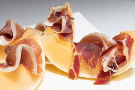 Delicious melon with thin slices of cured ham on a plateの写真素材