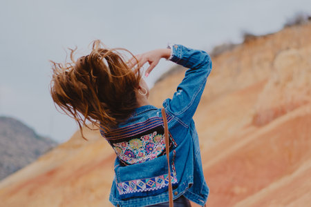 A back view of a female in a cool denim jacket flipping her hair