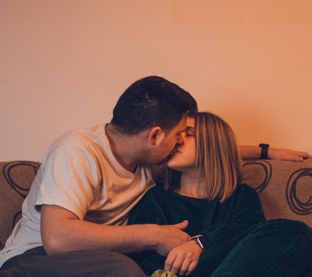 A couple in love sitting on the sofa and kissingの写真素材