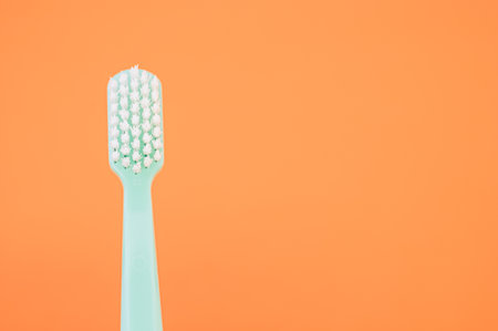 A closeup shot of a new green toothbrush on an orange backgroundの写真素材