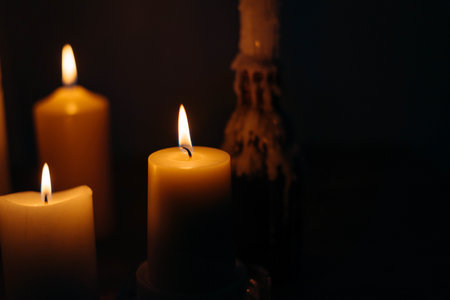 A closeup shot of burning candles in a dark roomの写真素材