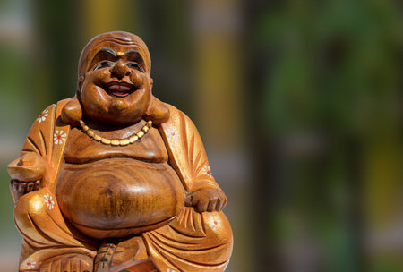 A closeup shot of a wooden statue of Buddha on a blurred backgrounの写真素材