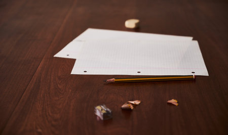 A closeup shot of blank papers, pencil shavings and an eraser on a wooden surface- copy spaceの写真素材