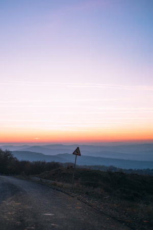 A vertical shot of a road with mountains in the background at scenic sunsetの写真素材