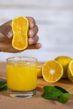 A man squeezing lemon into a glass with cut lemons on a wooden board in the backgroundの写真素材