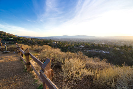 A landscape of grass field with wooden fence overlooking the city during sunrise