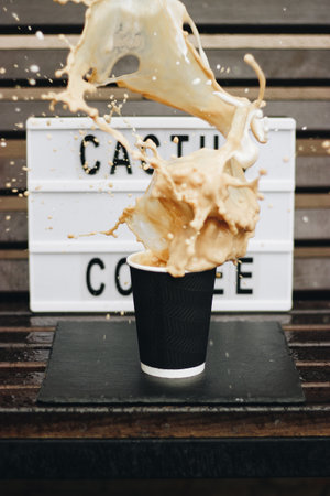 A closeup shot of a black plastic cup and a coffee pouring from it