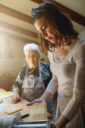 A happy Caucasian grandmother teaching her granddaughter to make a dough and bake with the family recipe - happy family conceptの写真素材