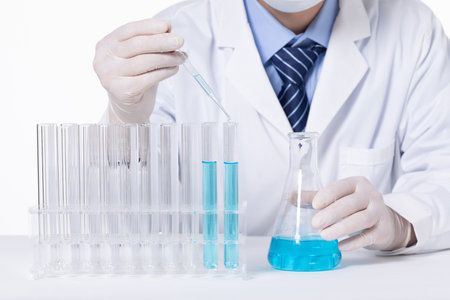 A closeup of a scientist experimenting with blue toxic substances in containers in a laboratoryの写真素材