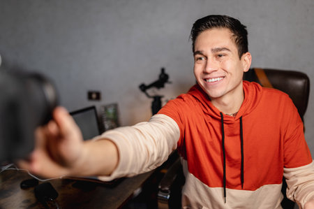 A young cheerful Hispanic social media influencer turning off the camera after finishing recording the video blogの写真素材