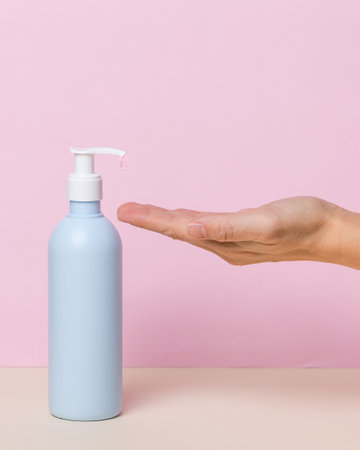 Female hand using alcohol gel sanitizer dispenser, against coronavirus . Antiseptic, Hygiene and Health concept. Minimalist style on pink backgroundの写真素材