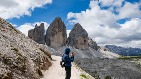 A hiker taking pictures from the view from the mountain peak under the cloudsの写真素材