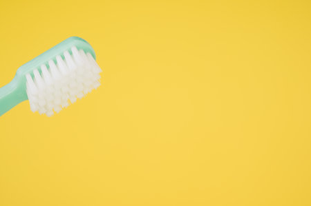 A closeup of a toothbrush isolated on yellow background with an empty space for a textの写真素材