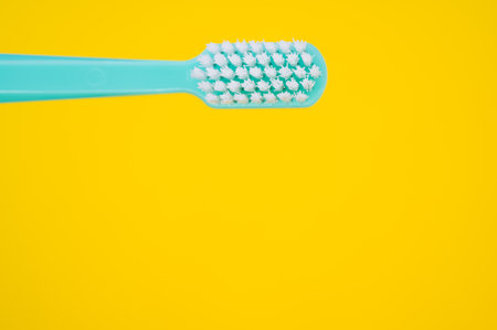 A closeup of a toothbrush isolated on yellow background with an empty space for a textの写真素材