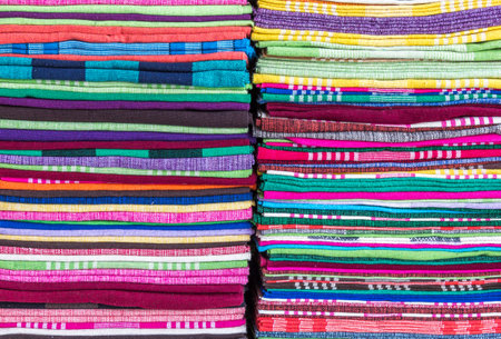 Colorful fabric and bath towels stacked in rows, pattern background.