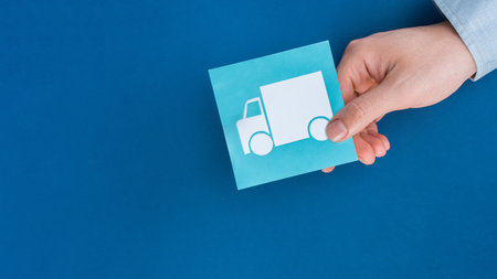 A closeup of a person holding a delivery truck sign isolated on a blue background