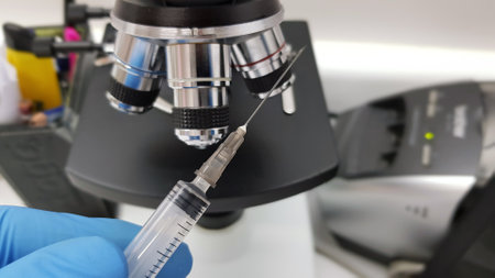 A doctor preparing syringe in a medical setup with a microscope in the background - covid- 19 vaccination conceptの写真素材