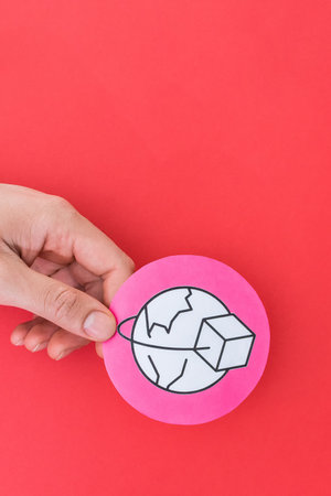 A vertical shot of a male hand holding an international trade shape symbol on red background