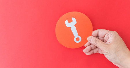 A female hand holding tool shape symbol on red background - service concept