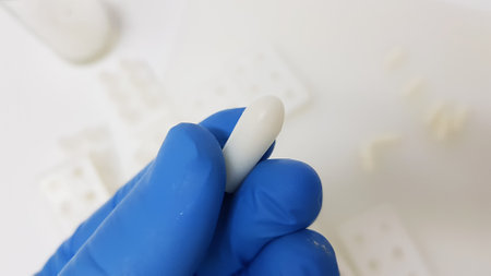A closeup shot of a scientist's or researcher's hand holding suppositories in the pharmacy...