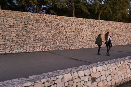 Two friends walking through a pathaway surrounded by rock walls in a park