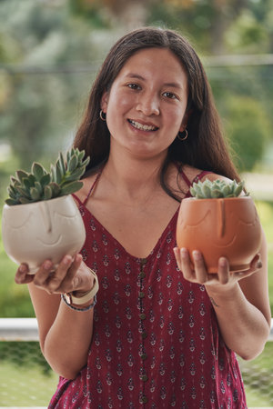 A young girl holding potted succulent plants and smilingの写真素材