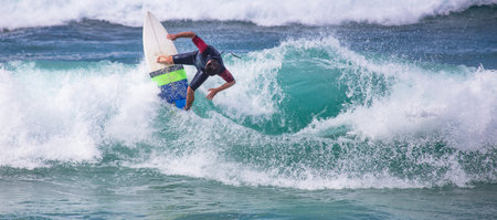 A panoramic shot of a surfer on the board in a wavy sea