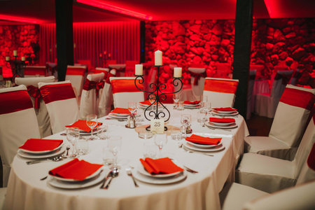 A closeup of prepared tables under red led lights for a wedding celebration in a restaurantの写真素材