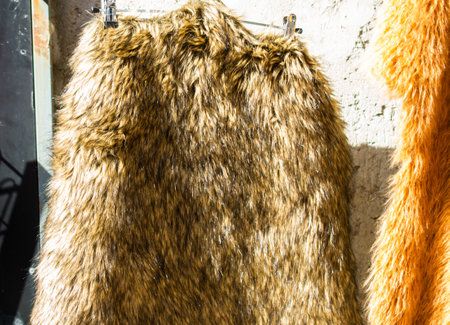 A closeup of a brown coat made of thick fur hanging from the metallic hanger