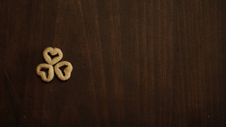 A top view shot of three tiny heart-shaped cereals on a wooden tableの写真素材