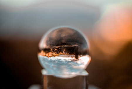 A selective focus shot of crystal glass ball with a reflection of trees in the snowの写真素材