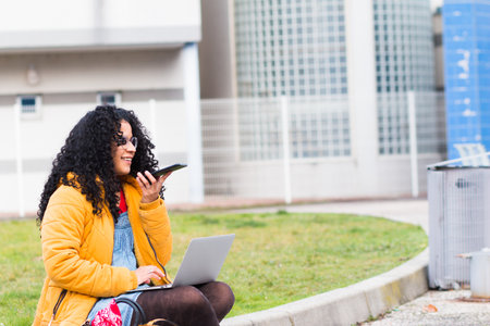 A young woman in the city with her cell phone and laptop